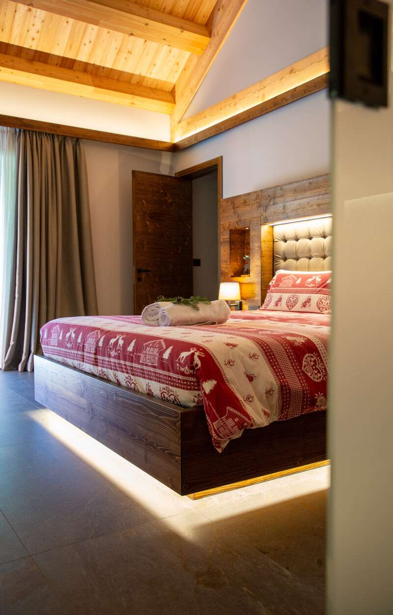 Dvoposteljna soba Chalet Cima delle Rondini v alpskem letovišču Kile v Valbruni Camera matrimoniale con soffitto in legno e illuminazione a led con luce calda dello Chalet Cima delle rondini al Kile Alpine Resort a Valbruna nella Val Saisera  in provincia di Udine